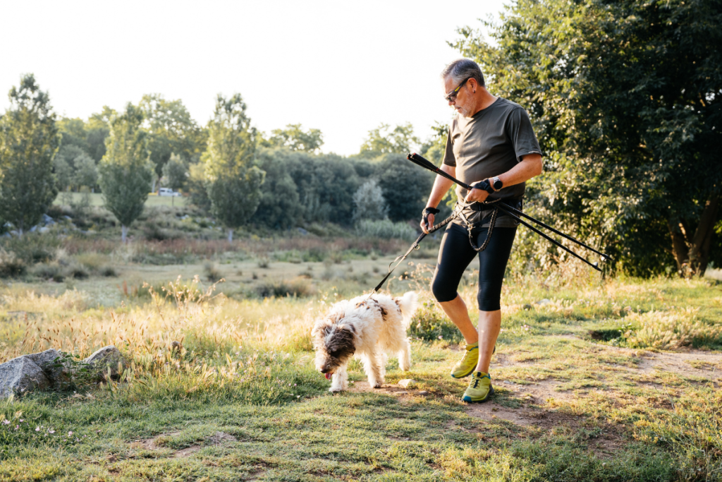 Un homme marche dans la nature avec son chien, équipé du baudrier de canicross